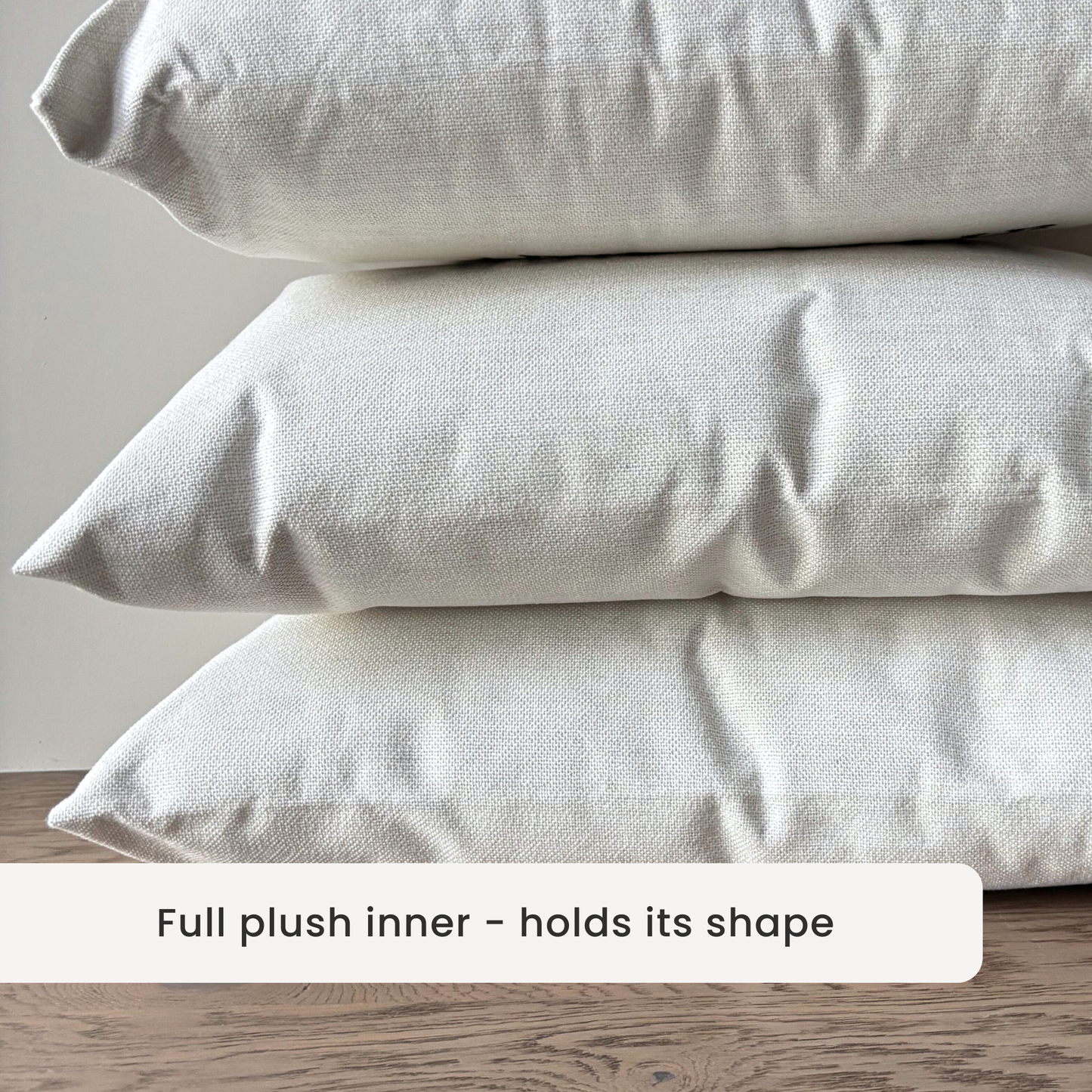 linen style fabric - Stack of three cushions on a wooden surface with a neutral background