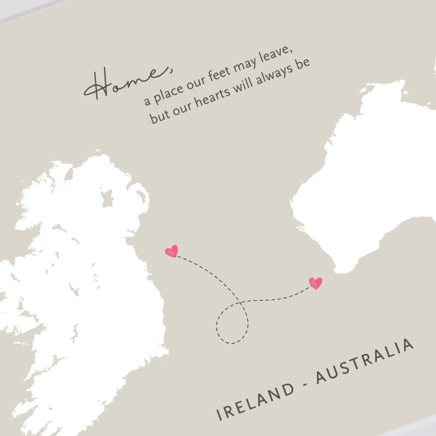 A minimalist map print with Ireland and Australia in white, a dotted dashed line connecting two small pink hearts, and the text 'Home, a place our feet may leave, but our hearts will always be' above, plus 'IRELAND - AUSTRALIA' at the bottom on a warm beige background.