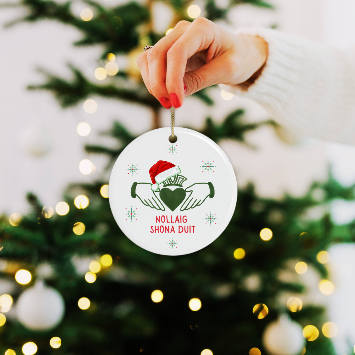 woman holding hanging Irish Claddagh Christmas ornament with Nollaig Shona Duit greeting and festive snowflakes