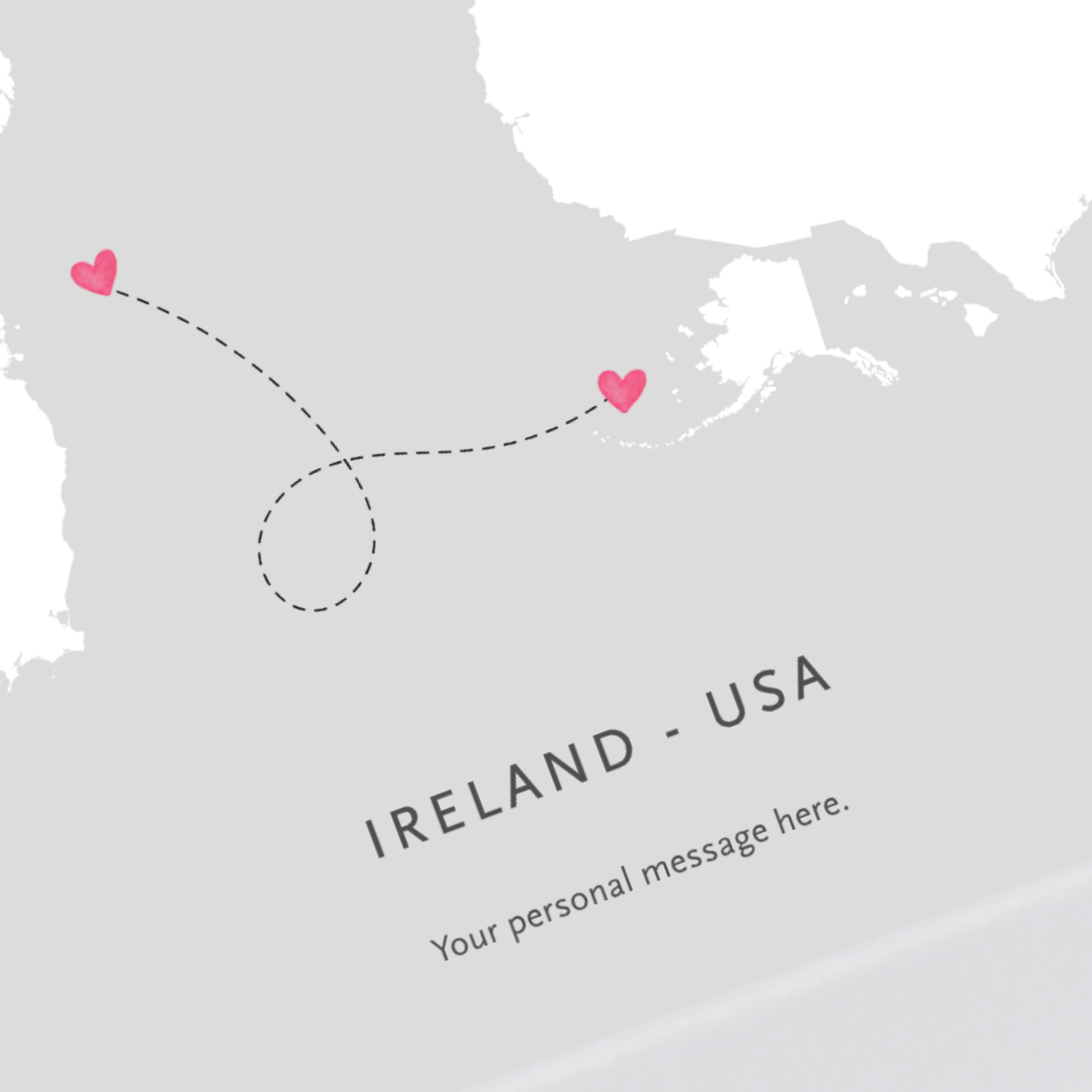 A minimalist travel-style map showing the outline of Ireland and the United States with a dashed flight path marked by two pink hearts. The text reads “IRELAND - USA” and “Your personal message here.