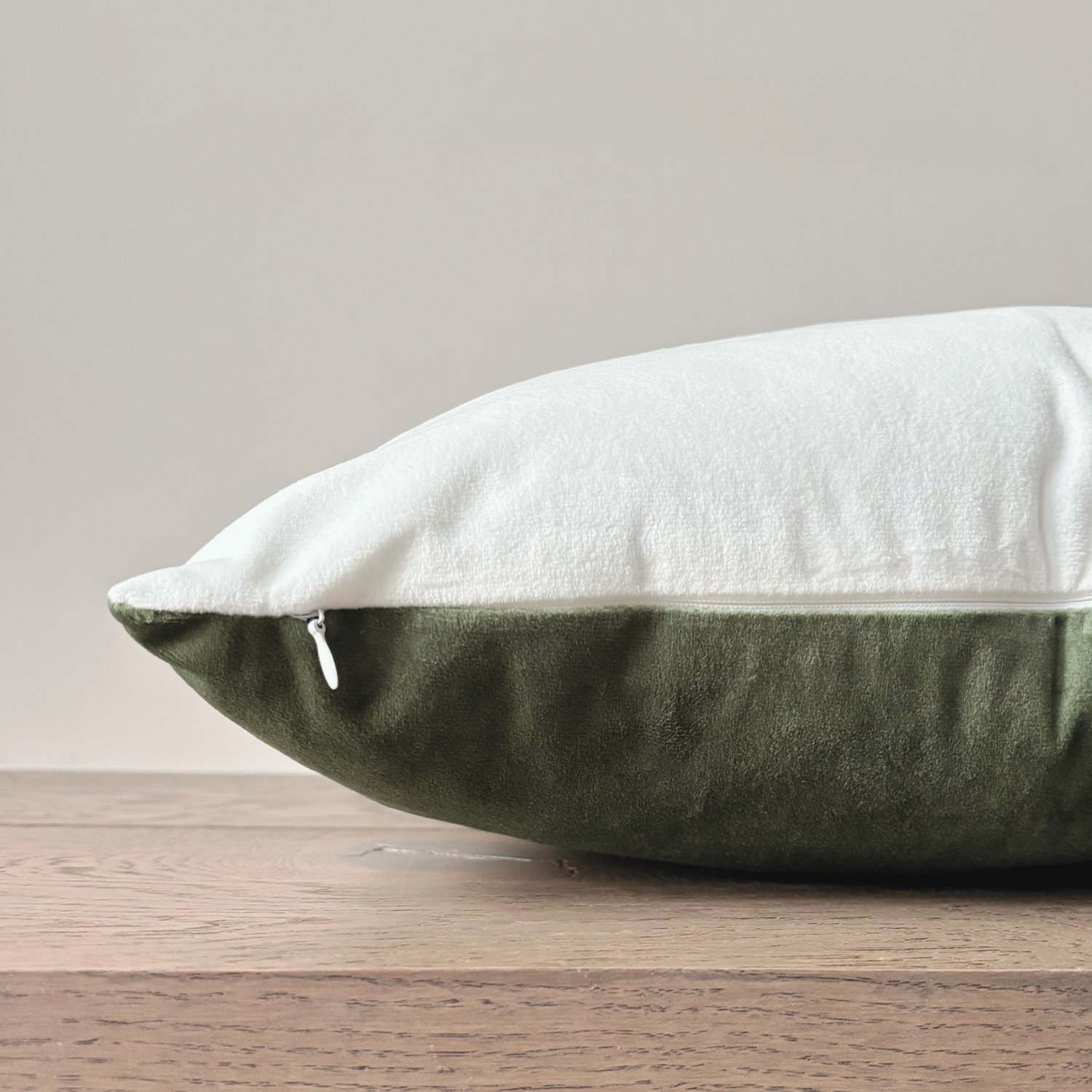 Green and white cushion on a wooden surface with a neutral background